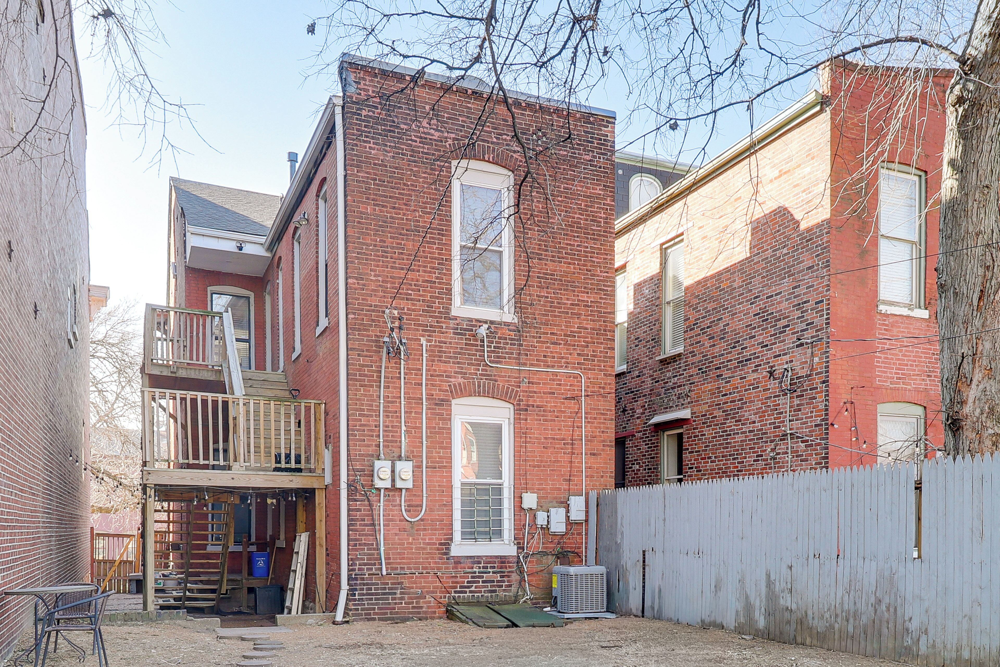 A brick building with a wooden deck and a fenced yard.