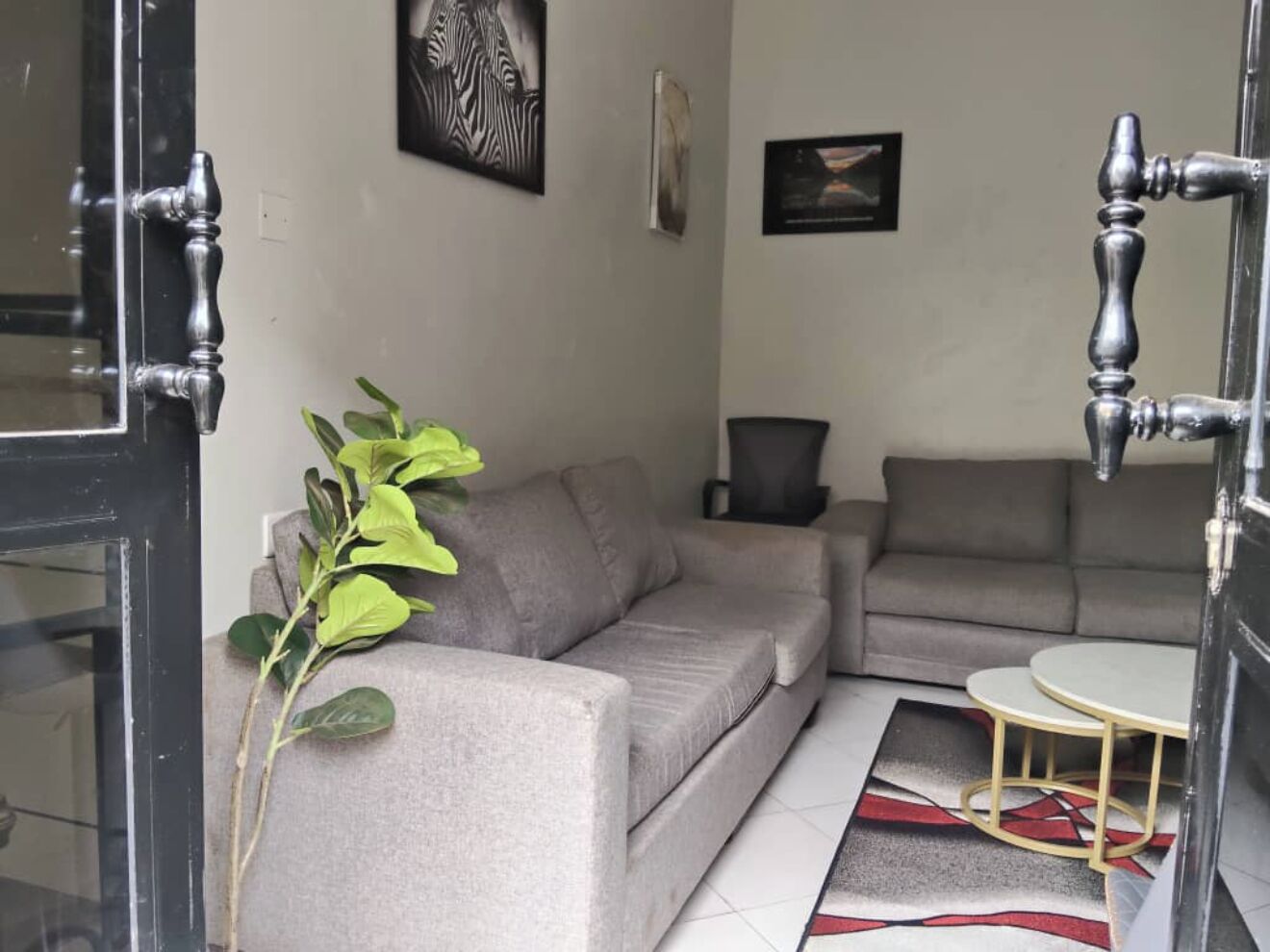 A living room with a grey sofa, a small round table, and a potted plant.