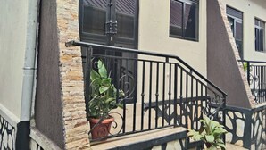 A building with a stone facade, black metal railings, and potted plants. - Quaint 1-bedroom apartment in pleasant Kampala neighborhood (Kampala)