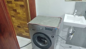 A compact, modern laundry room with a washing machine, a sink, and a tiled floor. - Quaint 1-bedroom apartment in pleasant Kampala neighborhood (Kampala)