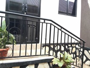 Una escalera de metal negro con una pared blanca y una ventana con contraventanas.