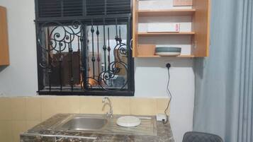 Una cucina compatta con lavello, piano di lavoro e finestra con inferriate decorative.