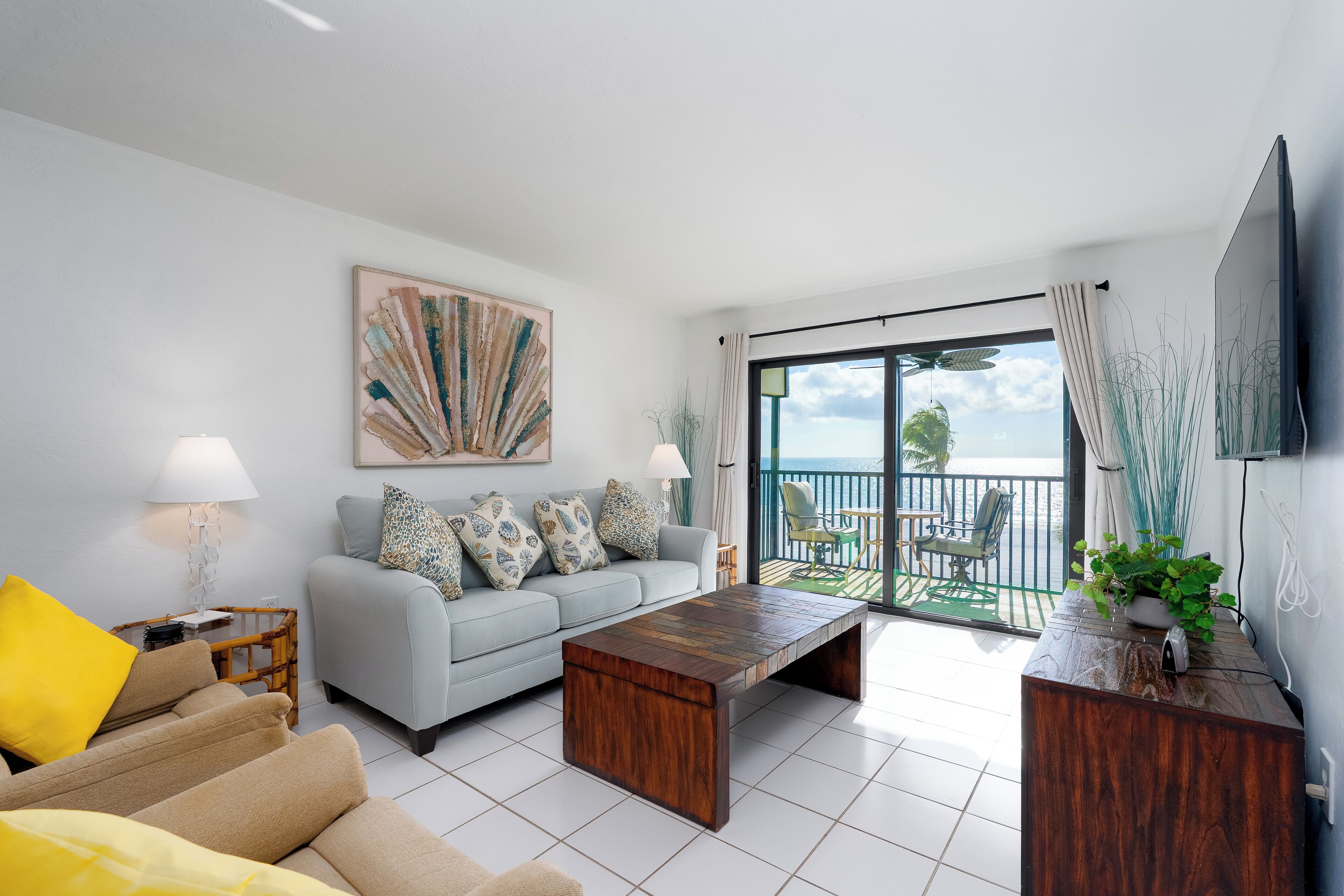 A modern living room with a sofa, coffee table, and a balcony with outdoor furniture.