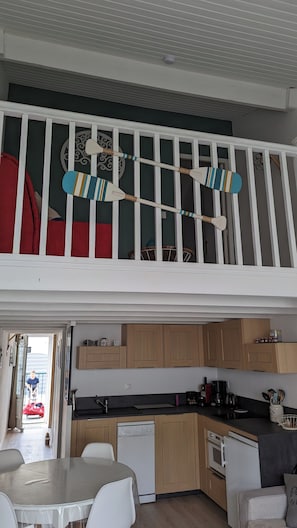 Eine Loft-Wohnung mit Küche, Essbereich und einem Balkon mit Geländer.