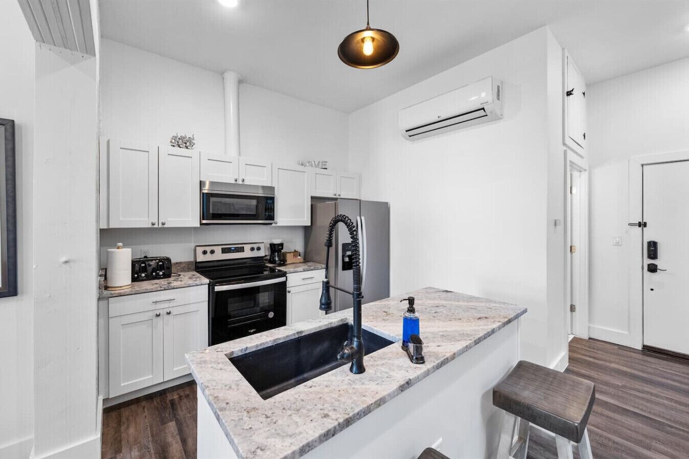 A modern kitchen with white cabinets, a built-in microwave, a stove, and a sink.