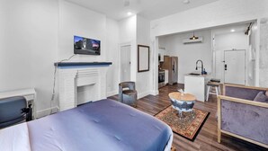 A modern hotel room with a large bed, a fireplace, a television, and a kitchenette in the background. - Brand-New on the OTR Streetcar Line (Cincinnati)