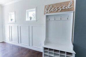 A hallway with white paneling, a bench with hooks, and a 'blessed' sign above. - 3-bedroom Modern Townhome in charming Lithonia! (Lithonia)