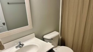 Un bagno con lavandino bianco, water e specchio.