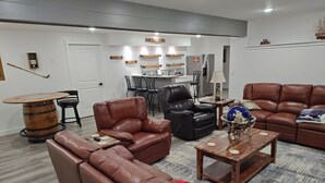 Ein Wohnzimmer mit Ledersofas, einem Couchtisch, einem Holzbottich und einem Essbereich mit Stühlen und einem Tisch.