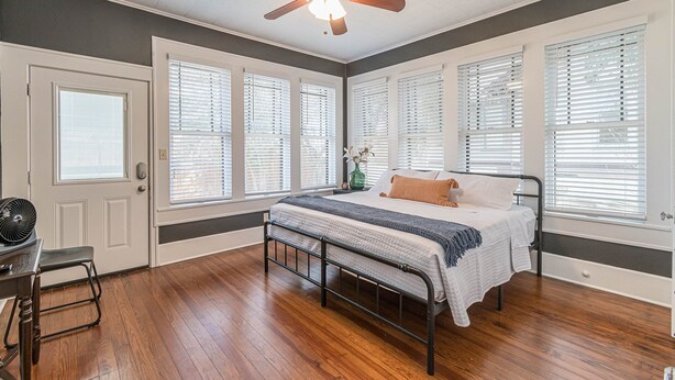 Une chambre à coucher avec un lit, un ventilateur de plafond, un bureau et une chaise.