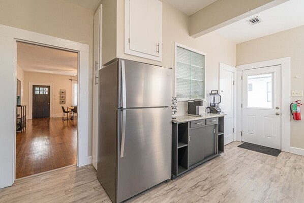 A modern kitchen with a stainless steel refrigerator, a coffee maker, and a microwave.