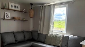 A modern living room with a grey sectional sofa, wooden coffee table, and shelves with decorative items.