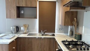 A modern kitchen with wooden cabinets, a stainless steel sink, a gas stove, and a coffee maker.