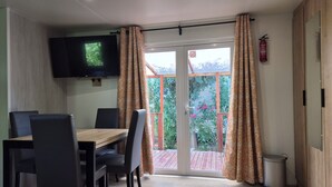 Ein Essbereich mit Tisch und Stühlen, einem an der Wand befestigten Fernseher und einer Glastür zum Außenbereich.