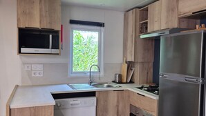 Eine moderne Küche mit Holzausstattung, einem Edelstahlkühlschrank, einer integrierten Mikrowelle und einem Fenster für natürliches Licht.