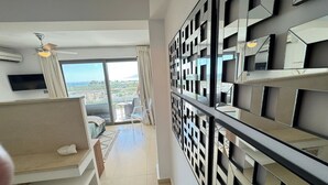 Een moderne hotelkamer met een groot raam, een plafondventilator, een flatscreen-tv, een bank en een decoratief paneel aan de muur.