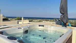 Een bubbelbad op een dak terras met uitzicht op zee.