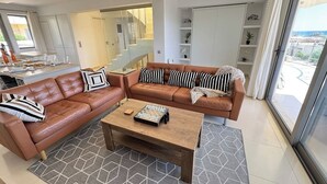 Een moderne woonkamer met een bruine leren bank, een houten salontafel en een schaakbord.