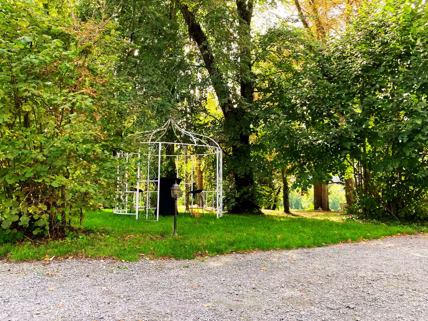 A gazebo in a wooded area with a gravel path leading to it.