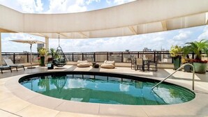 Zona de piscina en la azotea con sillones de descanso, una hamaca colgante y plantas en macetas.