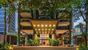 Una entrada de hotel moderna con un camino circular, varios balcones y plantas en macetas.