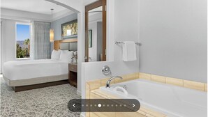 Une chambre d’hôtel avec un lit, une salle de bain avec une baignoire et une vue sur l’extérieur.