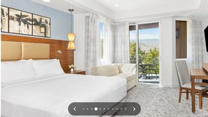 Une chambre d’hôtel avec un grand lit, un canapé, un bureau et un balcon avec vue.