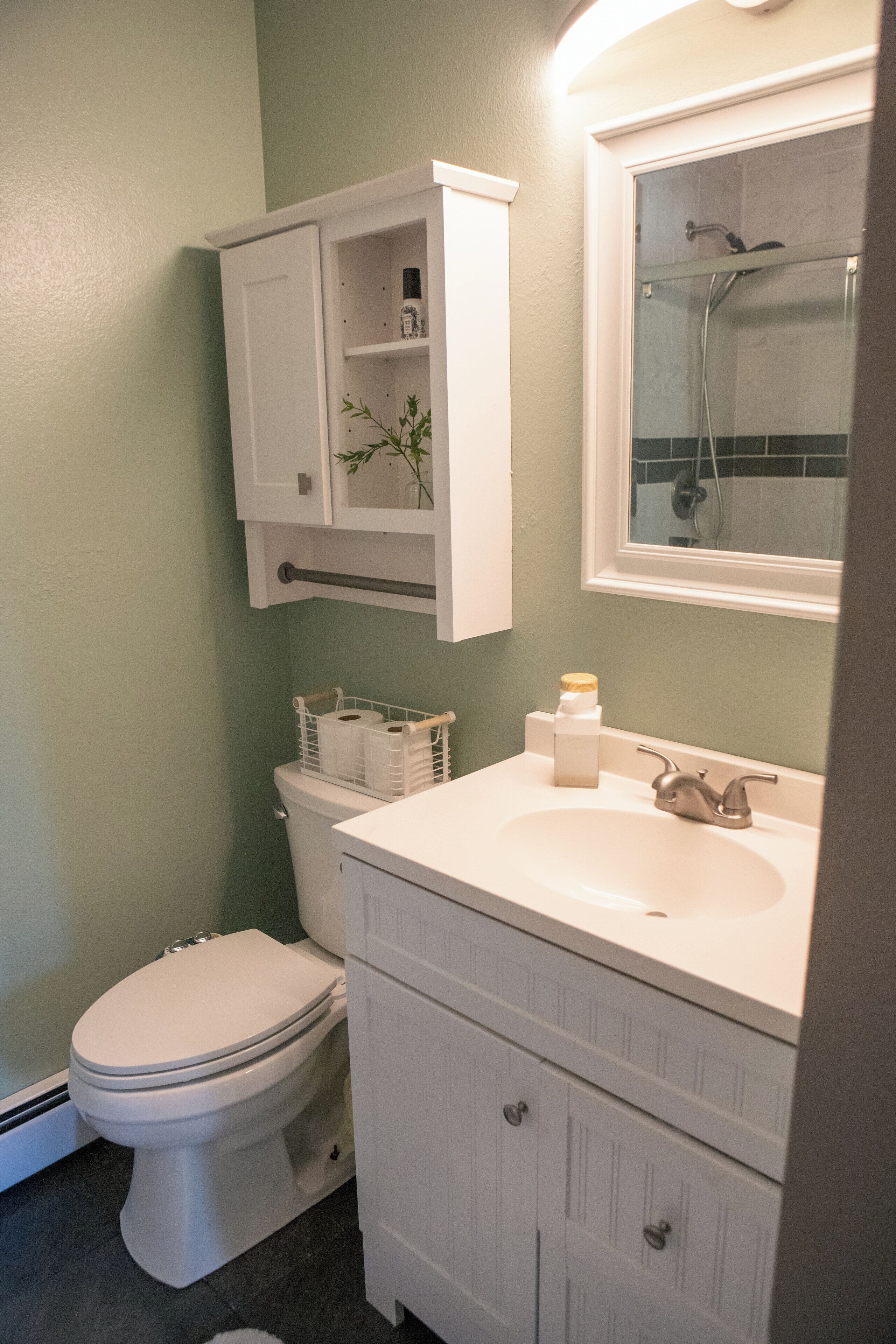 Een badkamer met een toilet, een wastafel en een spiegel.