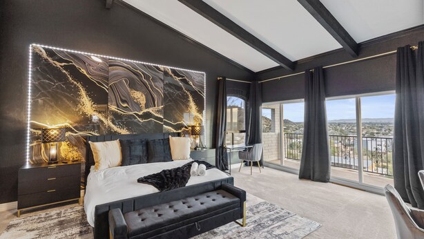 Ein modernes Schlafzimmer mit einem großen Bett, einem Kopfende mit Marmorstruktur und einem Balkon mit Blick.