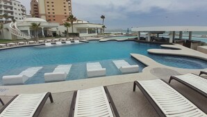 A swimming pool with lounge chairs and a view of the ocean. - Baja 404 Las Palmas Beachfront Resort (Puerto Peñasco)