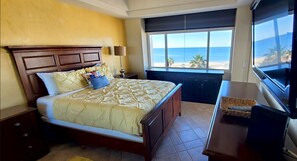 Ein Hotelzimmer mit Bett, Fernseher und Blick auf den Strand.
