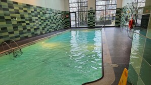 En inomhuspool med klart vatten, kaklade väggar och ett kaklat poolområde.