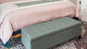 Een slaapkamer met een bed, een bankje, een plafondventilator, een wandlamp en een deur.