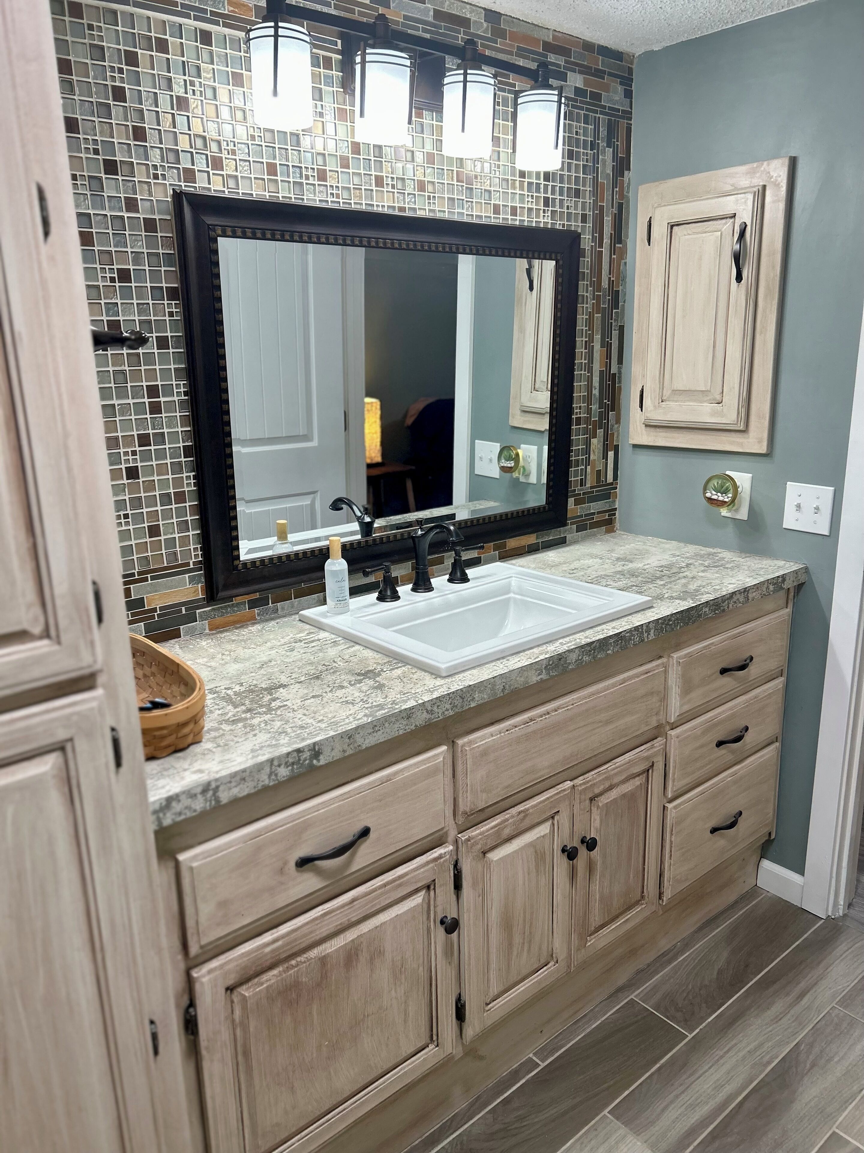 A bathroom with a large mirror, a double sink, and wooden cabinets.