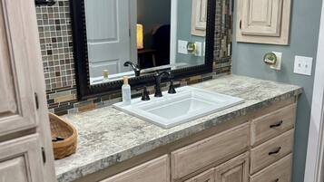 A bathroom with a large mirror, a double sink, and wooden cabinets.