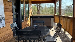 Une terrasse en bois couverte, avec une table et des chaises, un jacuzzi et un panneau indiquant « Wolf Pen Gap ».