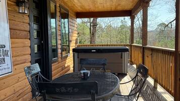 A covered wooden deck with a table and chairs, a hot tub, and a sign reading 'Wolf Pen Gap.'