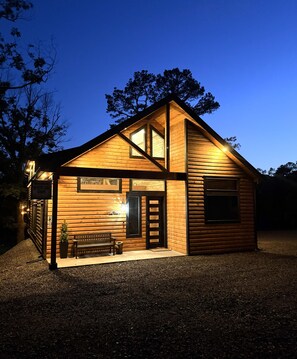 A wooden cabin with a bench and a sign that reads 'Welcome to White Oak Cabin.' - The White Oak Cabin at Cabins of Wolf Pen Gap (Mena)