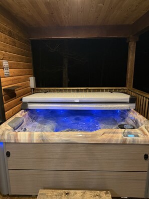 A hot tub with a wooden exterior, a control panel, and a wooden deck. - The White Oak Cabin at Cabins of Wolf Pen Gap (Mena)