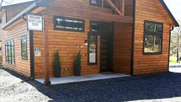 A cabin with a wooden exterior, a sign welcoming visitors, and a sign indicating the cabin is part of the Wolf Pen Gap.