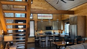 Une cuisine spacieuse avec des meubles en bois, un îlot central et un coin repas agrémenté d’un tapis rond.