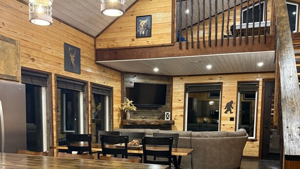 Une cuisine spacieuse avec un îlot central, un coin repas avec des chaises, un tabouret de bar, une cheminée et un ventilateur de plafond.