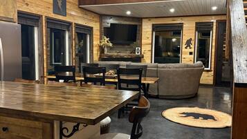 A spacious kitchen with a central island, dining area with chairs, a bar stool, a fireplace, and a ceiling fan.