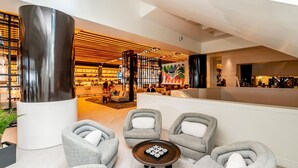 En modern entréhall med sittgrupper, en bar och en stor, dekorativ vägg.
