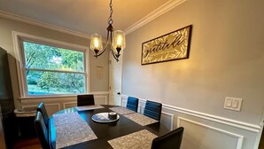 Une salle à manger avec une table ronde, des chaises noires et un lustre.