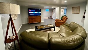 Un salon moderne avec un canapé en cuir, une table basse, un téléviseur et une lampe.
