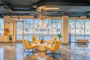 A modern lobby with a central seating area, large windows, and a visible street view. - The Access (Tempe)