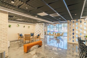 A modern lobby with a polished floor, wooden furniture, and a geometric wall design. - The Access (Tempe)
