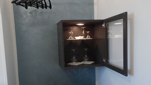 Une pièce compacte dotée d’une armoire intégrée, d’un petit meuble contenant des verres à vin et d’un réfrigérateur.