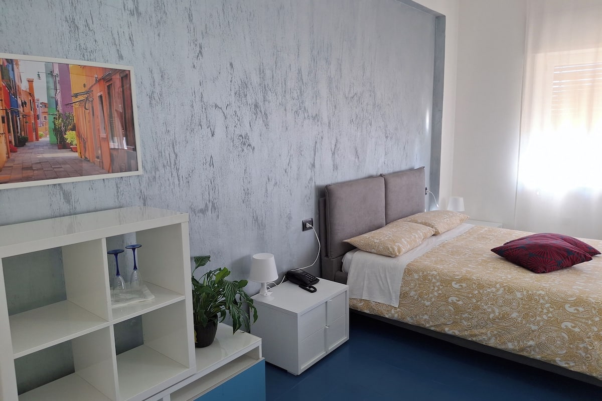A modern bedroom with a bed, bedside table, and a wall-mounted shelf.